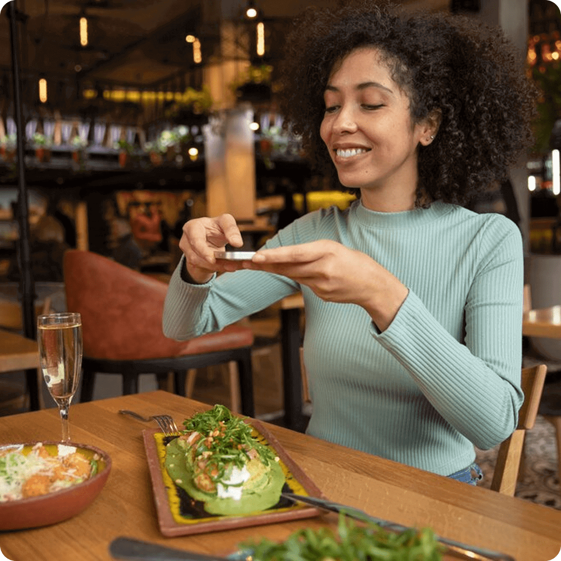 Person photographing food in a restaurant setting.