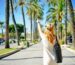 Woman walking along a palm tree avenue.